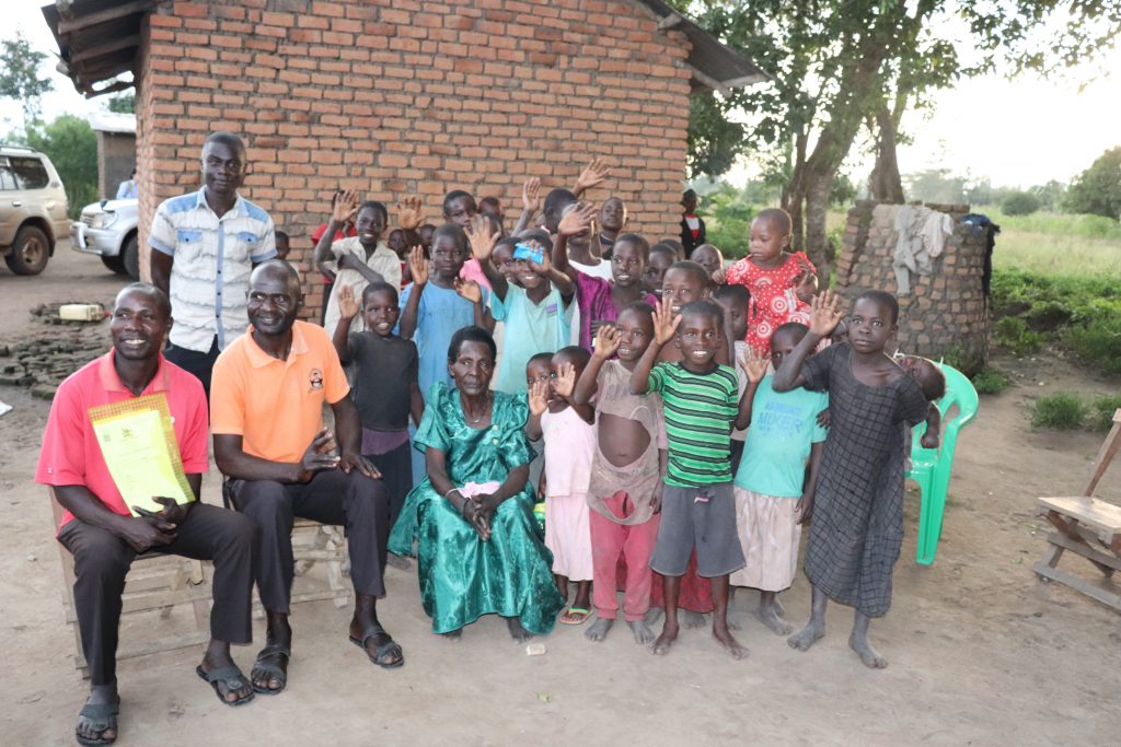 Kyofiina Hatira with some of her children and grandchildren; one of her sons holding a Certificates of Customary Ownership for her land